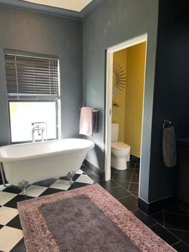 a bathroom with a white tub and a toilet at Franschhoek Guest Suite in Franschhoek