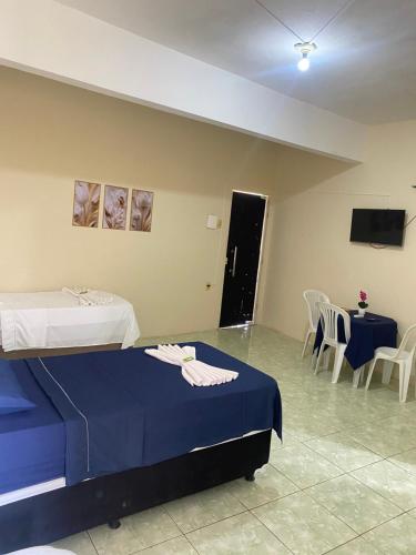 a room with two beds and a table and chairs at Hotel Renascer pojuca in Pojuca