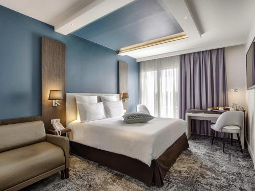 a hotel room with a bed and a chair at Mercure Cabourg Hôtel & Spa in Cabourg