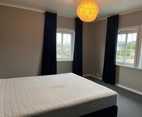 1 Schlafzimmer mit einem Bett, 2 Fenstern und einem Kronleuchter in der Unterkunft Feriehus med stort lekerom in Kristiansand