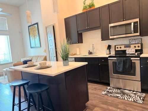 a kitchen with black cabinets and a kitchen island with stools at Charming 1-bedroom apartment in terrific Frisco next to Toyota Stadium with WiFi & fitness in Frisco