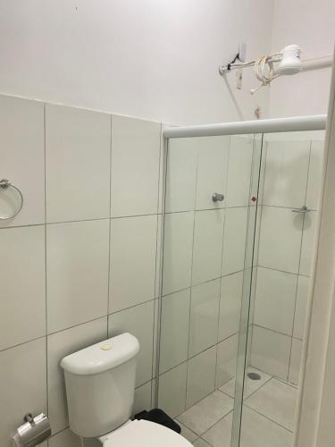 a white bathroom with a toilet and a shower at Hotel Renascer pojuca in Pojuca