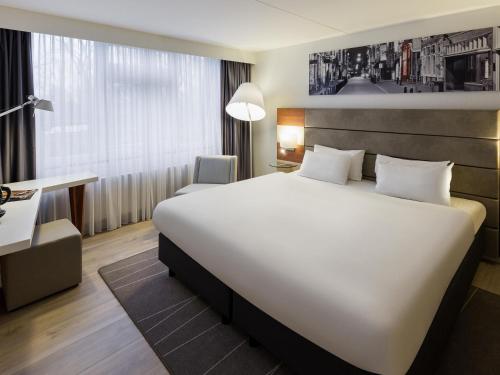 een hotelkamer met een groot wit bed en een bureau bij Mercure Hotel Amsterdam West in Amsterdam