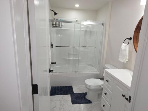a white bathroom with a shower and a toilet at Cozy Haven Suite in Moncton