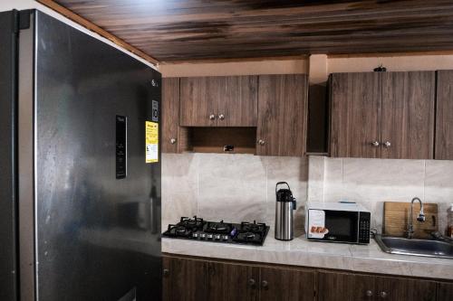 a kitchen with wooden cabinets and a stove and a microwave at Cabaña Kokkos Del Mar in Santa Marta