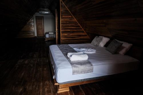 a bed in a wooden room with towels on it at Cabaña Kokkos Del Mar in Santa Marta
