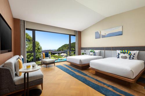 a bedroom with two beds and a tv and a couch at voco Ningbo Dongqian Lake by IHG in Ningbo