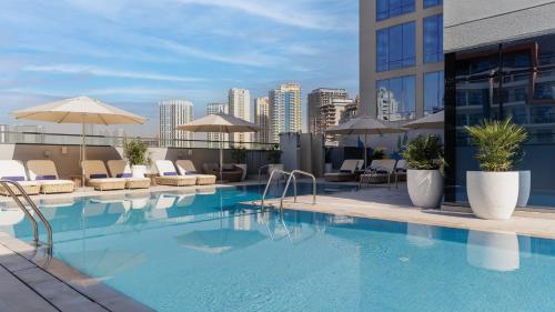 a swimming pool with chairs and umbrellas on a building at Holiday Inn Dubai Jumeirah Village Circle by IHG in Dubai
