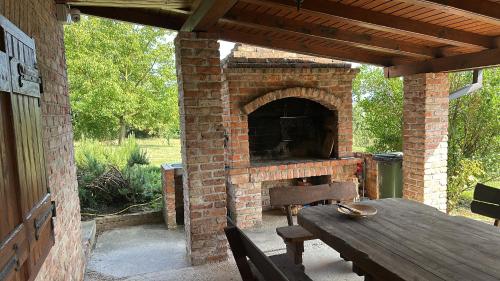 an outdoor patio with a brick oven with a wooden table at Podroom LauMarYvo in Dugo Selo