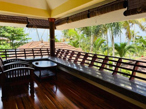 a balcony with a table and chairs and palm trees at Almond Villa in Kappil