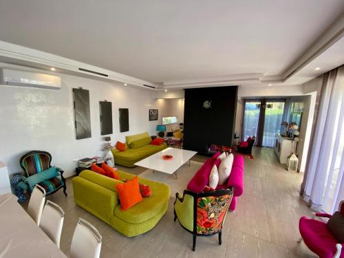 a living room with green couches and colorful chairs at Villa Zaara in Sehib Foukani