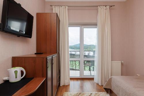 a bedroom with a bed and a television and a window at Вілла "Синевір" in Skhidnitsa