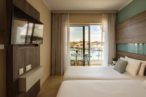 a hotel room with a bed and a balcony at 115 The Strand Hotel by NEU Collective in Il-Gżira