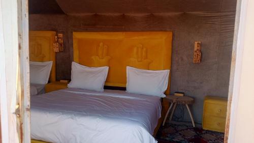 a bedroom with a bed with an orange headboard at Anssuf merzouga luxury camp in Merzouga