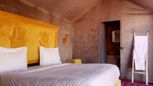 a bedroom with a large bed with white sheets at Anssuf merzouga luxury camp in Merzouga