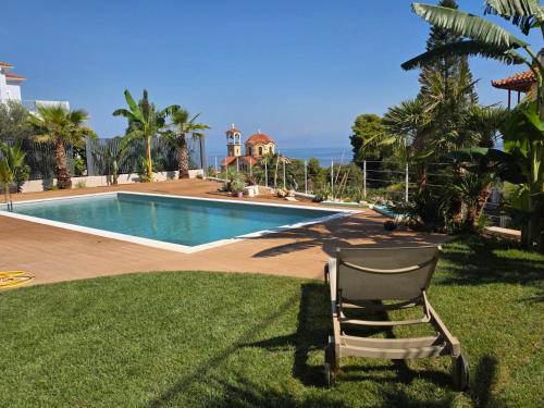 a chair sitting in the grass next to a swimming pool at Rastoni Studio Xylokastro 2 in Melission