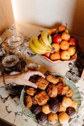Een persoon die een bord met eten pakt naast een fruitschaal. bij Strandstudio's Camperduin in Schoorl