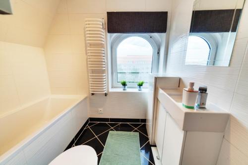 een badkamer met een bad, een toilet en een raam bij Dream Loft Motlava River in Gdańsk
