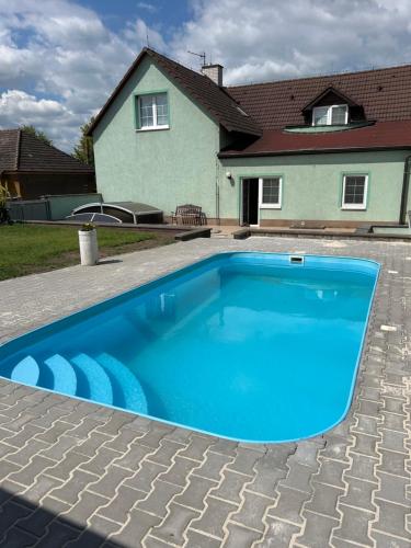 a blue swimming pool in front of a house at Útulný apartmán blízko Prahy in Zlonice