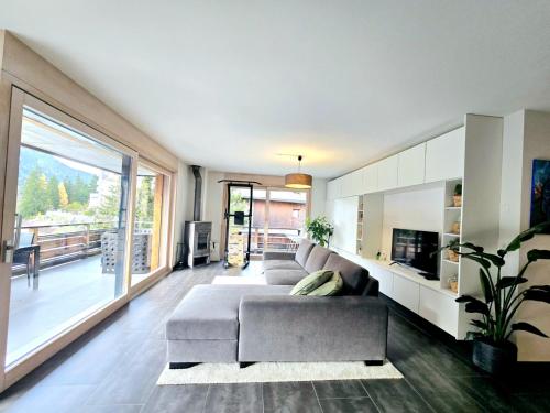 a living room with a couch and a large window at Champex Art Lodge in Orsières