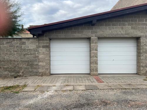 two white garage doors on a brick house at Útulný apartmán blízko Prahy in Zlonice