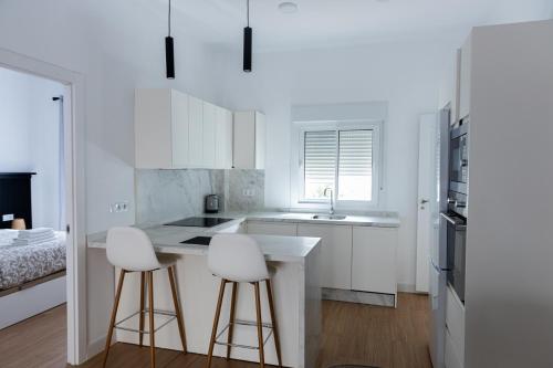 a kitchen with white cabinets and white bar stools at Lucky House in Seville
