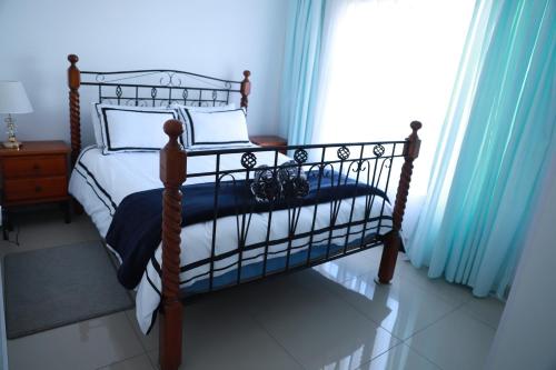 1 cama en un dormitorio con cortinas azules en Croydon Cove, en Port Alfred