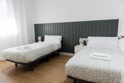 a bedroom with two beds and a black and white headboard at Lucky House in Seville
