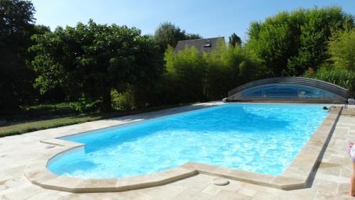 a large swimming pool in a yard with trees at Moulin de reigner in Anché