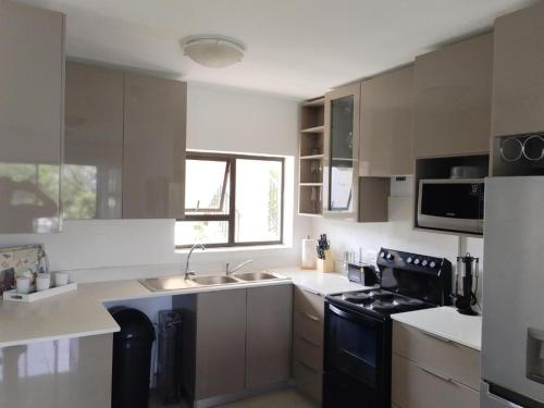 una cocina con fregadero y estufa horno superior en Croydon Cove, en Port Alfred