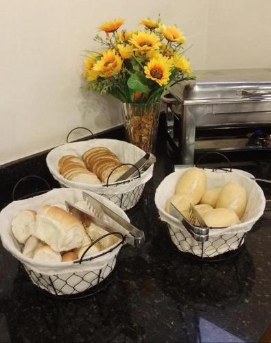 サンルイスにあるBoulevard Park Hotelのカウンターの上には花瓶に花が飾られたパンのバスケットが3つ
