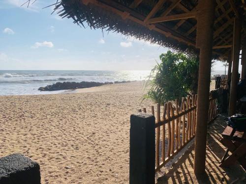 a beach with a wooden fence and the ocean at KAIMANA HOUSE - 3 Min walk to the beaches in Tangalle