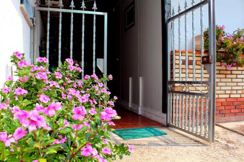 an open gate to a house with pink flowers at Residencial Pinho Verde in Mealhada