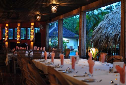 a dining room with white tables and chairs and windows at Kariwak Wellness Village, Hotel and Holistic Haven in Crown Point