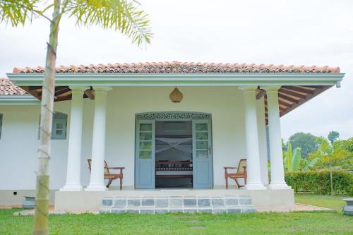 a white house with a porch with two chairs at KAIMANA HOUSE - 3 Min walk to the beaches in Tangalle
