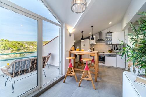 een keuken met een tafel en stoelen en een groot raam bij Villa Tudor Mit Atemberaubender Aussicht in Bobovišća