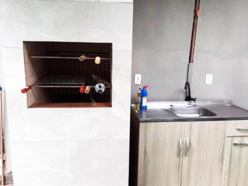 a kitchen with a sink and a microwave at Casa com piscina aquecida e área de festas no litoral in Ilhota