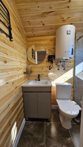 a wooden bathroom with a toilet and a sink at Aiwa Eco Hotel in Karakol