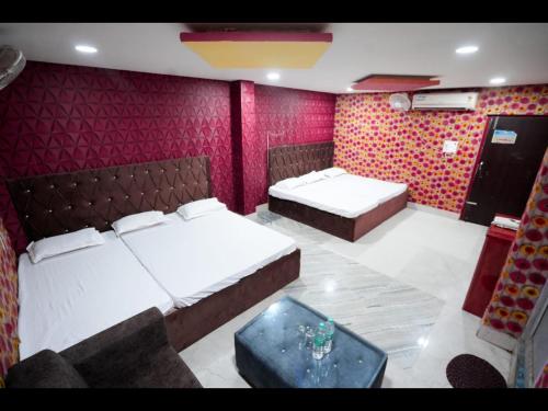 a bedroom with two beds and a red wall at Hotel Parinay Vatika - Deoghar in Deoghar