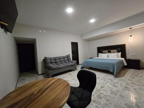 a bedroom with a bed and a table and a couch at Suites & Lofts Olivier in Uruapan del Progreso
