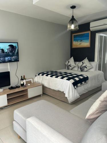 a bedroom with a bed and a flat screen tv at Home Away From Home 6 minutes away from beach in Cape Town