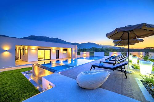 a villa with a swimming pool and an umbrella at Haus In Georgioupoli Mit Außenpool Und Atemberaubender Aussicht in Kavros