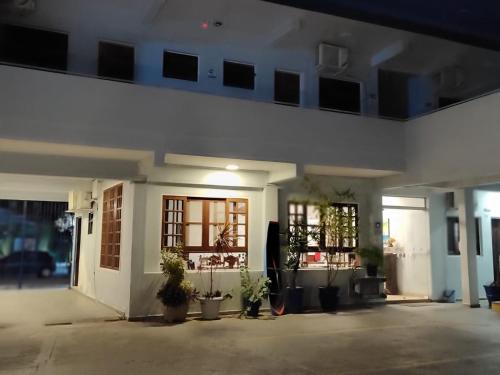 Un edificio blanco con plantas en macetas delante. en Hotel Pousada Garoupas, en São Sebastião