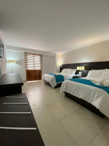 a large bedroom with two beds and a desk at Hotel María del Carmen in Jalpan de Serra