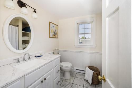 a white bathroom with a toilet and a mirror at The Boathouse in Kennebunkport