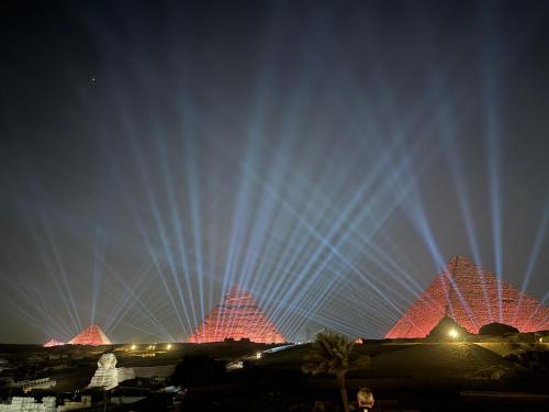 a group of pyramids lit up at night at The Gate Hotel Front Pyramids & Sphinx View in Cairo