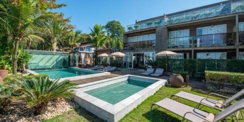 a swimming pool in front of a building at Hotel Spa Nau Royal in Camburi