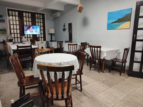Un comedor con mesas y sillas y un televisor. en Hotel Pousada Garoupas, en São Sebastião