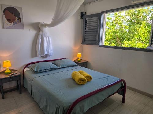a bedroom with a bed with two yellow towels on it at Lauramar Avocado - Vue Mer et Montagne in Le Morne aux Bœufs