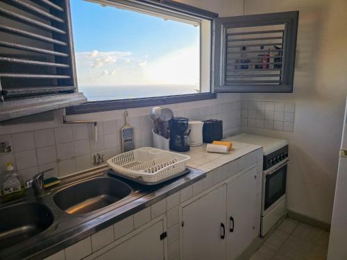 a small kitchen with a sink and a window at Lauramar Avocado - Vue Mer et Montagne in Le Morne aux Bœufs